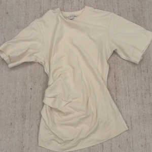 Beige t-shirt från Off-White - En stilren beige t-shirt från Off-White med klassisk rund hals och avslappnad passform. Perfekt basic-plagg att matcha med jeans eller shorts. Tillverkad i mjuk bomull för skön känsla hela dagen.