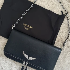 Svart axelväska från Zadig & Voltaire - Snygg svart axelväska från Zadig & Voltaire i skinn med silverfärgad kedjerem. Den har aldrig använts och är därför ny! Väskan medföljer även en längre kedja utöver den på bilden☺️