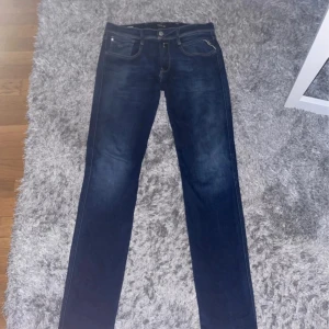 Replay anbass - Säljer ett par snygga blå jeans från Replay med klassisk femficksdesign och ljusa kontrastsömmar. Jeansen har raka ben och normal passform, med Replay-logga på bakfickan och knapp. Perfekta till din vardagsstil!
