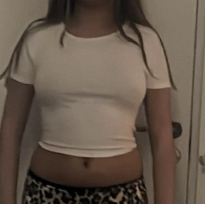 Vit croppad topp med knyt i ryggen - Säljer en vit croppad topp med korta ärmar och snygg knytning i ryggen. Toppen har en tight passform och är perfekt för dig som gillar en enkel men trendig stil. Materialet känns mjukt och stretchigt, vilket gör den bekväm att bära hela dagen.