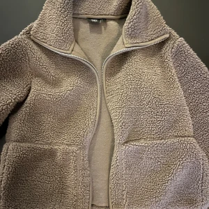 Beige teddyjacka med dragkedja - Mysig brun teddyjacka från 157 med hög krage och hel dragkedja framtill. Som ny! Nypris 350:-