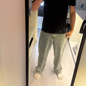 Baggy ljusblå jeans - Säljer ett par baggy ljusblå jeans med klassisk femficksdesign och rak passform. Jeansen har hög midja och är tillverkade i denim med en tvättad look. Perfekta för en avslappnad och trendig stil.