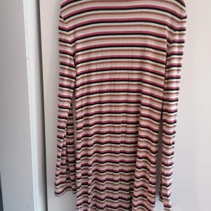 Randig ribbad klänning i rosa och brunt - Säljer en långärmad ribbad klänning från Cubus i storlek 158/164. Klänningen har horisontella ränder i rosa, brunt, vitt och svart. Den är stretchig och har en smickrande passform som passar perfekt till dig som gillar färg och mönster. Klänningen passar även storlek 34-36