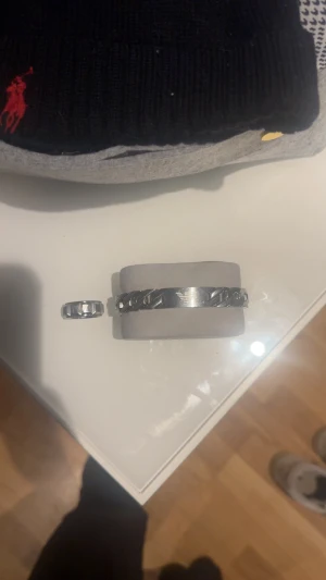Emporio Armani silverfärgat set - Snyggt set från Emporio Armani med ett silverfärgat armband i kedjedesign och en matchande ring. Båda har det klassiska Armani-logot med gravyr på framsidan. Armbandet har en bred länk och ringen har en cool, kantig form som sticker ut.