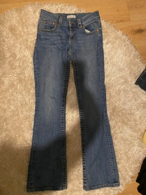 Blå bootcut jeans från Gina tricot - Blåa jeans från Gina tricot storlek 36, med fickor som går att öppna och stänga.