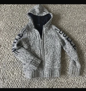 Grå stickad hoodie/jacka från Selected homme - Tröjan/fleecejackan har huva, dragkedja framtill och ribbade muddar vid ärmslut och nederkant. Perfekt för dig som gillar streetstyle och vill ha något extra.