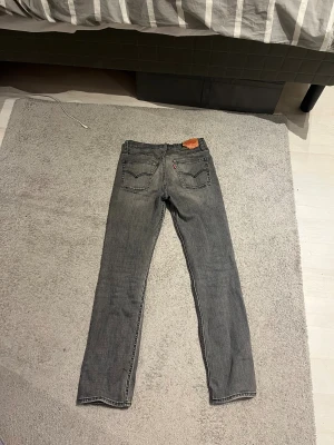 Grå Levi's 501 jeans straight fit - Säljer ett par grå Levi's 501 jeans med klassisk straight fit/slim. Jeansen har en snygg tvättad look, ikonisk läderpatch bak och röda Levi's-tag på fickan. Tillverkade i slitstarkt denim-material, perfekta för dig som gillar tidlös stil.