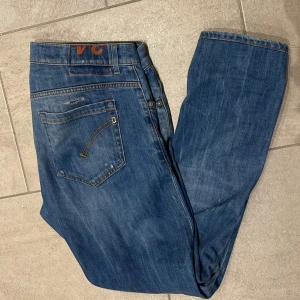 Dondup jeans - Snygga blå jeans från dondup i skinny fit med slitna detaljer och hål framtill för en cool, avslappnad look. Klassisk femficksmodell med orange sömmar och raka ben. Perfekt för dig som gillar streetstyle och vill sticka ut. Jeans sitter som 33/31