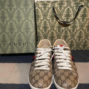 Gucci sneakers med GG-mönster, strl 42 - Säljer ett par klassiska Gucci sneakers i beige med GG-monogram över hela skon och röda/blå ränder på sidan. Skorna har vita snören och vit sula. Materialet är canvas med skinn-detaljer. Perfekta för dig som vill sticka ut med lyxig streetstyle.