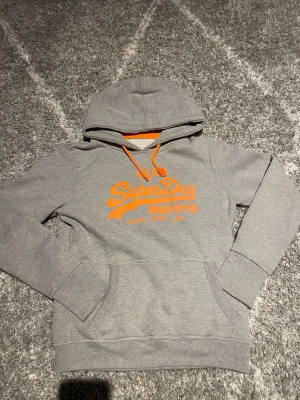 Superdry hoodie grå - En grå riktigt snygg Superdry hoodie som passar M men det står L väldigt bra skick och vid frågor är det bara att skriva 