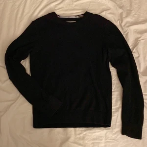 Svart stickad tröja - Säljer en stilren svart stickad tröja med rund halsringning och ribbade detaljer. Perfekt för kyligare dagar och enkel att matcha med olika outfits.