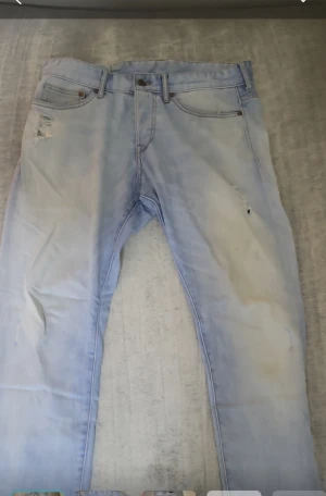 Ljusblå slim jeans från Denim, 32/32 - Säljer ett par ljusblå slim fit jeans från denim med låg midja. Jeansen har klassisk femficksdesign, slitningar och är tillverkade i bomullsdenim. Perfekta för en avslappnad och trendig look.