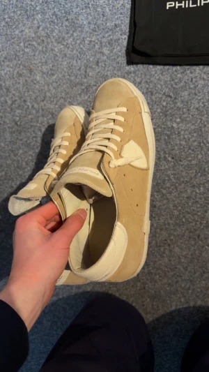 Beige Philippe Model sneakers i mocka - Snygga beige sneakers från Philippe Model Paris med platt sula och rund tå. Skorna är tillverkade i mjuk mocka med detaljer i skinn och har klassisk snörning. Stilren design med logotyp på sidan och tungan. Perfekta för dig som gillar exklusiva sneakers. Använda 2 gånger då de är för små. Nypris 4000 mitt pris 2500!! Pris går självklart att diskuteras! Hör av dig vid frågor🙏🏻 skick 10/10 inga defekter. Box och dustag tillkommer självklart