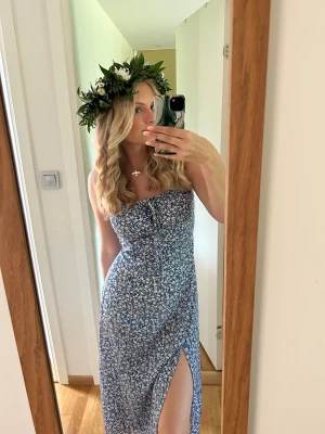 Blommig blå långklänning med slits - Säljer en superfin blå långklänning med vita små blommor och en snygg slits framtill från SHEIN. Klänningen   har en söt snörningsdetalj vid bysten. Perfekt för sommarens alla tillfällen tex midsommar🤩 