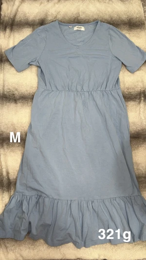 Ljusblå klänning med volangkant - Supersöt ljusblå klänning från bonprix med v-ringning, korta ärmar och resår i midjan. Klänningen har en volangkant nertill som ger en extra touch. Perfekt för varma dagar och enkel att styla med sneakers eller sandaler.🌸 Fint använt skick. Storlek M