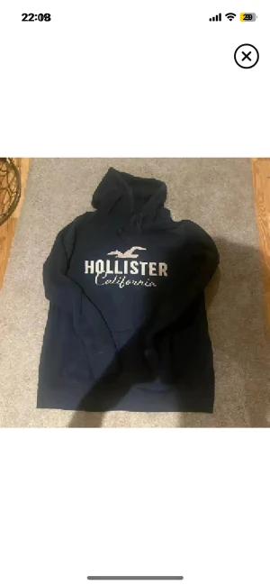 Mörkblå Hollister hoodie med tryck - Hollister hoodie i fint skick utan defekter alls. Strl L på den men sitter super på s/m