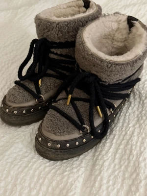 INUIKII Curly rock vinterskor - Heeej!  Säljer mina fina bekväma INUIKIIS då jag nyss köpt nya. Storleken är 37.  Passar mig som hoppar mellan 36-37! Modellen är täckt med varmt fårskinn på ovandelen och insidan, med små nitar på sidorna, vilket gör dessa sååå coola och unika! Haft de i ca 1 år. Lite smutsiga, som lätt går att tvätta bort då de endast är lera/grus, men inga andra skavanker som jag lägger märke till! Nypris: 3999 på NK, mitt pris 2500!