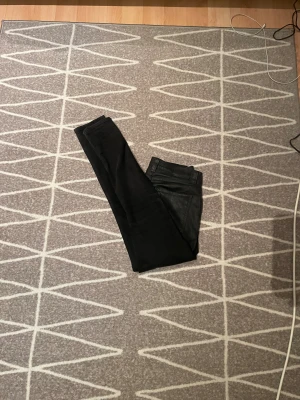 Svarta jeans från Nudie Jeans, W30 L32 - Säljer ett par svarta jeans från Nudie Jeans i storlek W30 L32. Jeansen är tillverkade av 100% ekologisk bomull och har en klassisk femficksdesign. Perfekta för dig som gillar stilrena och tidlösa svarta jeans.