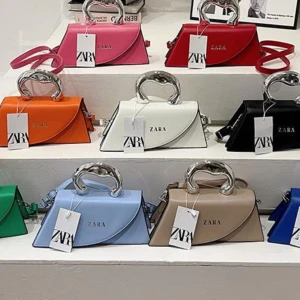 Färgglad handväska från Zara - Snygg handväska från Zara i flera färger som rosa, röd, orange, vit, svart, grön, blå, beige och ljusblå. Väskan har en unik form med silvrigt handtag och axelrem. Perfekt för att addera färg till din outfit och rymmer det viktigaste.