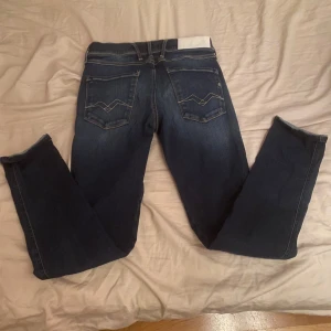Mörkblå Replay jeans, midwaist, W28 L32 - Säljer ett par mörkblå jeans från Replay med klassisk femficksdesign och snygga kontrastsömmar. Jeansen har raka ben och coola broderade detaljer på bakfickorna. Midjan är normal och materialet är mjukt denim som sitter skönt hela dagen.