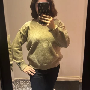 Beige v-ringad stickad tröja - Mysig beige stickad tröja från Gina Tricot med v-ringning och ribbade muddar vid ärmslut och nederkant. Perfekt för lager-på-lager och passar till jeans eller kjol. Klassisk och enkel design som funkar året runt.