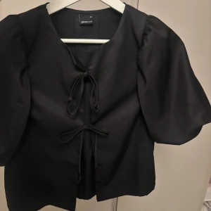 Svart blus med puffärm från Gina Tricot - Säljer en svart blus från Gina Tricot med puffiga korta ärmar och snygg snörning framtill💕endast testad