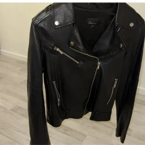 Svart skinnjacka med dragkedjor - Lite sliten vid kragen (se sista bilden) 