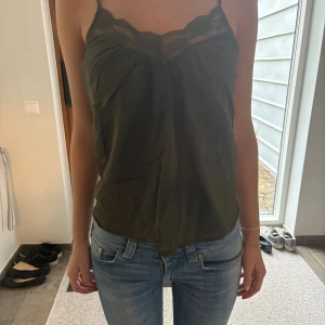 Olivgrön linnetopp med spetsdetalj - Säljer en olivgrön linnetopp med tunna axelband och från custommade 