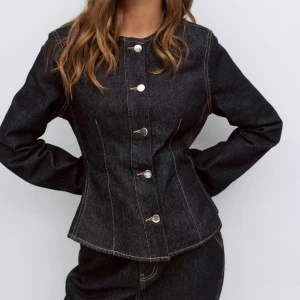 Peplum denim jacket - Snygg jeansjacka från Gina Tricot med markerad midja, rund halsringning, långa ärmar och silverfärgade knappar framtill. Perfekt för dig som gillar en stilren och modern look. Oanvänd!