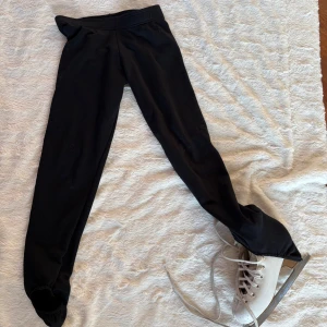 Svarta skridskoleggings från Mondor - Svarta leggings från Mondor i Polartec-material, perfekta för konståkning. De är tighta och stretchiga med hög midja och designade för att dras över skridskorna. Snygg och funktionell modell som håller dig varm på isen. Mycket bra skick förutom två små hål framtil som kan enkelt sys ihop av den händige (se bild 5)