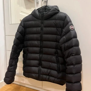 Svart dunjacka från Colmar med huva - Svart dunjacka från Colmar med huva och dragkedja framtill. Jackan har inga skavanker!