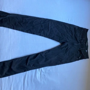 Svarta Replay jeans, midja 28/32 - Svarta jeans från Replay med klassisk femficksdesign och diskret logga vid fickan. Jeansen har smal passform och raka ben, tillverkade i mjukt bomullsmaterial med lite stretch för extra komfort. Perfekta för en stilren och enkel look.