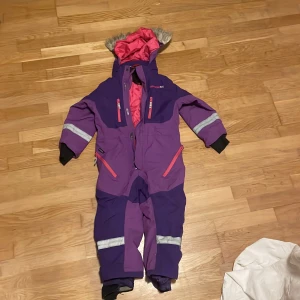 Rosa/lila overall  - Superfin overall i lila och rosa nyanser, perfekt för både vardag och äventyr. Tillverkad i mjukt och slitstarkt material som ger hög komfort och rörelsefrihet.