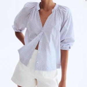 Blårandig skjorta med puffärm från hm - Snygg blårandig skjorta med puffiga långärmar och v-ringad hals. Skjortan har knappar framtill och är tillverkad i mjuk bomull. Perfekt för dig som gillar en avslappnad men trendig stil.