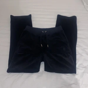 Svarta velourshorts Juicy Couture XXS - Svarta shorts från Juicy Couture i mjuk velour med snörning i midjan och fickor med silvriga knappar bak. Klassisk logga på snörändarna och relaxed fit. Perfekta för en chill och trendig look. Använda ganska mycket men inget slitage eller nåt annat❤️