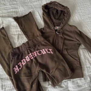 Bruna mjukisbyxor Hidden Cult XS - Bruna mjukisbyxor och tröja från Hidden Cult med rosa broderad logga i storlek xxs, tighta modellen. Har kommit till användning endast en gång därav säljer jag det. Dustbag finns även med 