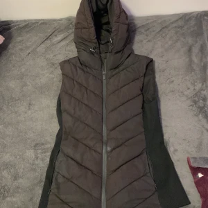 Svart lång pufferjacka från Zara - Säljer en svart lång pufferjacka från Zara med huva och snörning. Jackan har dragkedja framtill, sidofickor med dragkedja och quiltad design i diagonala linjer. Ärmarna är svarta och materialet känns mjukt och varmt, perfekt för kyliga dagar. Har inte använt den så mycket jag köpte den för 600kr men jag säljer den för 350kr 