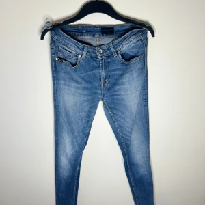 Tiger of Sweden jeans  - Snygga ljusblå jeans från Tiger of Sweden i modellen Slight. Jeansen har klassisk femficksdesign, skinny passform och är tillverkade i mjukt denim med orangea sömmar. Perfekta för dig som gillar en smal siluett och stilren look. Jeansen har en liten defekt med ett hål på sidan som syns i bilderna annars skit bra jeans, frågor/funderingar hör av dig 🤙🏽 