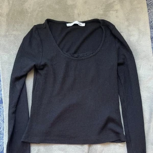 Svart ribbad långärmad topp 157 - Svart långärmad topp från 157 med ribbad struktur och rundad halsringning. Enkel och stilren modell som passar perfekt till jeans eller kjol. Tillverkad i mjukt material för en bekväm känsla hela dagen.