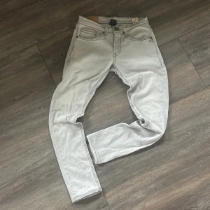 Ljusgrå dondup jeans, storlek 30 - Snygga ljusgrå jeans från dondup i klassisk femficksmodell. Jeansen har raka ben, normal passform och tydliga kontrastsömmar. Tillverkade i mjukt jeanstyg med diskret dondup-logga på bakfickan. Perfekta för dig som gillar stilrena och ljusa jeans. Slim-fit!