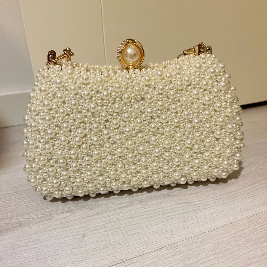 Vit pärlbeströdd kuvertväska med gulddetaljer