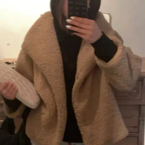 Beige teddyjacka med bred krage - Säljer en beige teddyjacka med bred krage och avslappnad passform. Jackan är gjord i mjukt fleece-material och har långa ärmar. Perfekt för dig som vill ha en mysig och trendig look under kyliga dagar💕