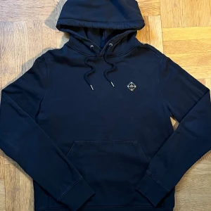 Svart J Lindeberg Hoodie - Svart J Lindeberg Hoodie                                     Bra skick 8,5/10 ✅                                          Storlek M 👕                                                    Material bomull 🧶                                                Färg svart 🎨                                                          Mått B 51 /L 67 cm📐                                      Fraktar senast dagen efter 🚚💨 Priset går att diskutera vid en snabb och smidig affär. Det är bara att höra av dig vid frågor