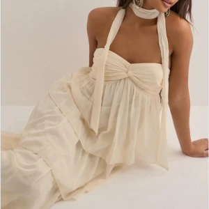 SLUTSÅLD långklänning  - Vill kolla intresset för denna drömmig långklänning i champagnefärgad, tunn och luftig med flera lager volanger. Klänningen är axelbandslös med olika knyt möjligheter (se bilder).   och snygg omlottkänsla upptill. Helt slutsåld på hemsidan. Perfekt klänning till midsommar, fest, dejt eller andra tillfällen. Endast använd vid ett tillfälle så nyskick och väl omhändertagen. Nypris 700kr🩷