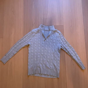 Ljusgrå stickad tröja med half zip - ljusgrå stickad tröja med kabelstickat mönster. Sitter bra på den som är mellan 155 cm - 170 cm. Half zip 