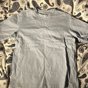 Ljusblå relaxed t-shirt från H&M - En enkel och stilren ljusgrå t-shirt från H&M i relaxed fit. 