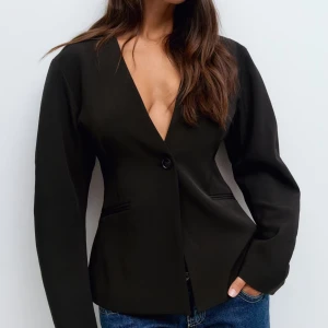 Svart kavaj  - Snygg svart kavaj från Gina Tricot med djup v-ringning och en knapp framtill. Nypris 699kr endast använd en gång! 