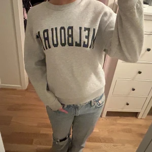 Grå sweatshirt 'Melbourne' Gina Tricot - Grå sweatshirt från Gina Tricot med mörkblå text 'Melbourne' framtill. 
