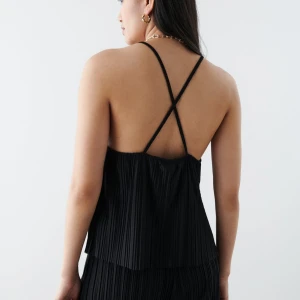 svart linnetopp med smala band - Oanvänd. Denna tröja är från Bianca Ingrosso kollektion med Gina tricot, modellen är ”Tamara singlet”. Plisserat linne med tunna axelband som korsas i ryggen. Linnet är svart och har rynkade detaljer vid halsringningen. Denna tröja säljs inte längre. Skriv till mig om du vill se hur tröjan sitter på modellen.  Vänligen läs min bio innan du gör ett köp; där hittar du bland annat information om leveransprocessen med mera 😊