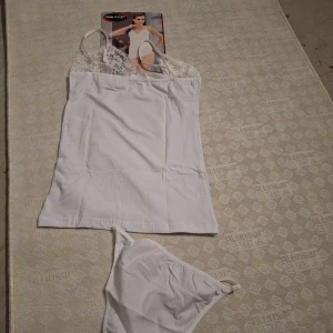 Vit spetsdetaljerad linnetopp - Säljer en vit linnetopp från Doraluks med tunna axelband och vacker spets upptill. Toppen är ärmlös och har en feminin, enkel design som passar perfekt till jeans eller kjol. Materialet är mjukt och stretchigt för en bekväm känsla.